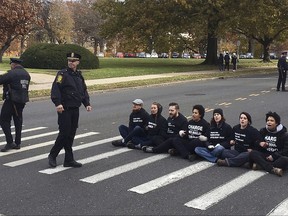 People sit in a street outside the state Capitol on Monday, Nov. 27, 2017, in Hartford, Conn., to demonstrate the handling of the case of Jayson Negron, 15, killed by police in May in Bridgeport. The seven protesters were arrested. Community advocates had called for a rally to bring attention to Negron's death and to call for prosecutors to release video evidence in the case. (AP Photo/Dave Collins)