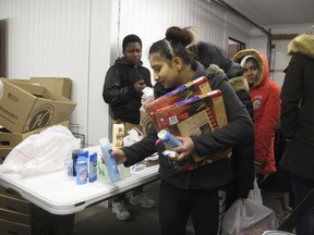 In this Nov. 16, 2017 photo Fargo residents pick up food, personal hygiene items and laundry soap at a food pantry run by students of the Legacy Children's Foundation. The pantry is the first student-run operation in the city and served about 150 children and 125 adults in its first week of operation. The students order food, stock shelves, follow a budget and recruit others for food drives. (AP Photo/Dave Kolpack)