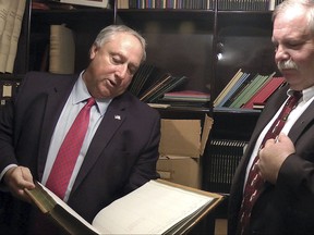 Terry Pfaff, left, chief of staff, New Hampshire House of Representatives, inspects a book found in a vault at the Statehouse, Monday, Nov. 27, 2017, in Concord, N.H. Beside him is House Speaker Shawn Jasper, right. The vault, which had been locked for decades in a room that once served as the state treasury in the 1800s, is now assigned to the Senate Finance Committee. (AP Photo/Holly Ramer)