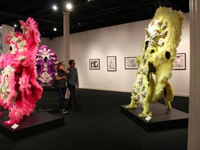 In this Friday, Nov. 17, 2017 photo, Kim Rorschach, director of the Seattle Art Museum, and the museum's curator of contemporary art, Catharina Manchanda, look at Mardi Gras Indian costumes made by Darryl Montana, on display at the New Orleans Jazz Museum in New Orleans. Prospect.4 opens Sunday and ends Feb. 25. It's the fourth such exhibit and includes photographs, sculptures, prints, videos and other work, much of it avant-garde, by 73 artists from around the world.  (AP Photo/Janet McConnaughey)