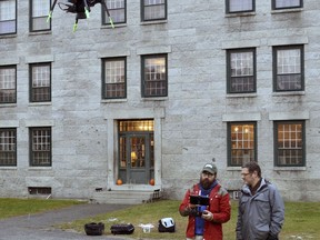 In this Nov. 14, 2017 photo, Dartmouth's Chad Hill, left, and Jesse Casana watch as their drone equipped with a thermal imaging camera flies around the site of a Shaker Village in Enfield, N.H. The camera uses the heat differences between stone and the soil surrounding it to identify structures below the surface, which then can be further explored. The two researchers are using the equipment at six archaeological sites around the world. (AP Photo/Michael Casey)