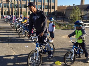 In this Oct. 3, 2017, photo, second-graders learn to ride bikes on the school yard from physical education teacher Terrance Chavis at Seaton Elementary School in Washington. At a time when elementary and high schools are all about getting students ready for college or jobs, physical education teachers are being urged to look beyond graduation, too, to make lifelong movers out of even the least competitive kids. (AP Photo/Maria Danilova)
