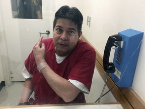 Escaped hospital patient Randall Saito points to a guard as he sits in an inmate visitor's booth at San Joaquin County Jail before a scheduled court hearing in French Camp, Calif., Friday, Nov. 17, 2017. Saito, who escaped from a psychiatric hospital in Hawaii, was captured as the result of a tip from a taxi cab driver. (AP Photo/Terry Chea)
