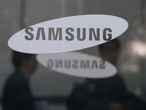 FILE - In this Oct. 31, 2017, file photo, employees walk past logos of the Samsung Electronics Co. at its office in Seoul, South Korea. Overturning an appeals court's decision, South Korea's Supreme Court says on Tuesday, Nov. 14, 2017, a family of a Samsung worker who died of brain tumor should be eligible for state compensation for occupational disease. (AP Photo/Ahn Young-joon, File)