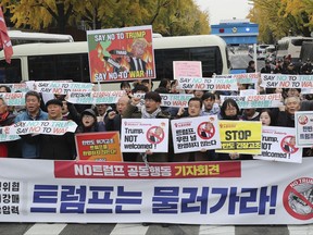 South Korean protesters stage a rally to oppose a visit by U.S. President Donald Trump near the presidential Blue House in Seoul, South Korea, Tuesday, Nov. 7, 2017. The signs held by protesters read: "We oppose Trump's visit." (Han Jong-chan/Yonhap via AP)