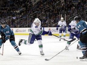 San Jose Sharks' Marc-Edouard Vlasic, right, stops a shot from Vancouver Canucks' Brock Boeser, center, during the first period of an NHL hockey game Saturday, Nov. 11, 2017, in San Jose, Calif. (AP Photo/Marcio Jose Sanchez)