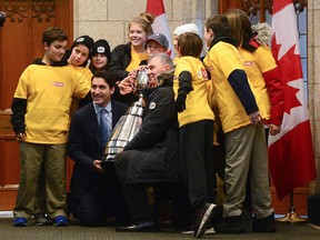 Prime Minister Justin Trudeau and CFL commissioner Randy Ambrosie join The Tigers, a youth flag football team from Orleans. Ont., for a photo with the Grey Cup outside the Prime Ministers office on Parliament Hill in Ottawa on Tuesday, Nov.21, 2017. THE CANADIAN PRESS/Sean Kilpatrick