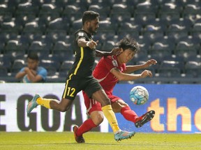 Malaysia's Kunanlan Subramaniam, left, and North Korea's Jong IL Gwan battle for the ball during their Asian Cup qualifiers soccer match at Thunder Castle stadium in Buriram province, Thailand, Friday, Nov. 10, 2017. North Korea beat Malaysia 4-1 . (AP Photo/Sakchai Lalit)
