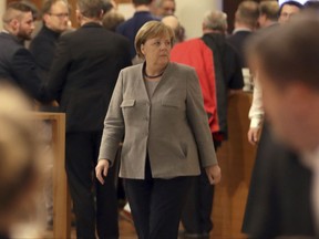 German Chancellor and chairwomen of the German Christian Democratic Union (CDU), Angela Merkel, center, walks in lobby of the representation of the German state of Baden-Wuerttemberg during exploratory talks on a coalition between the CDU, the Christian Social Union (CSU), the German Liberal Party (FDP) and the Green Party in Berlin, Germany, Sunday, Nov. 19, 2017. (AP Photo/Michael Sohn)