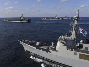 In this Nov. 12, 2017 photo, three U.S. aircraft carriers USS Theodore Roosevelt, top left, USS Ronald Reagan, top center, and USS Nimitz, top right, participate with South Korean Navy's Aegis destroyer, King Sejong the Great, bottom, during joint naval exercises.