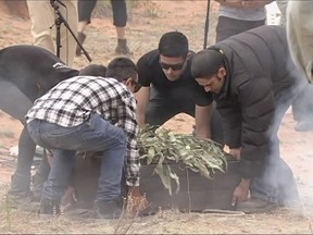 In this image made from video, the oldest human remains in a coffin are unloaded and placed on the ground during a traditional ceremony in Lake Mungo, Australia, Friday, Nov. 17, 2017.  The human remains found in Australia have been returned to the Outback desert that he roamed some 42,000 years ago in a ceremony celebrated by traditional owners. The ice age Aborigine was dubbed Mungo Man after the dry salt Lake Mungo where he was found in 1974 in remote New South Wales state, west of Sydney. (Australian Broadcasting Corporation via AP)