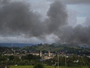 FILE - In this June 9, 2017, file photo, black smoke from continuing military air strikes rises above a mosque in Marawi city, southern Philippines. The human rights group Amnesty International said in a report on Friday, Nov. 17, 2017, it has documented a variety of serious violations of humanitarian law, some amounting to war crimes, during the five-month conflict between Philippine government troops and Islamic State-allied militants who laid siege to the southern city of Marawi. .(AP Photo/Aaron Favila, File)