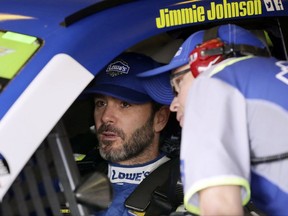 Jimmie Johnson, left, talks to a crew member in the garage during a practice session for Sunday's NASCAR Cup series auto race at Texas Motor Speedway in Fort Worth, Texas, Friday, Nov. 3, 2017. (AP Photo/LM Otero)