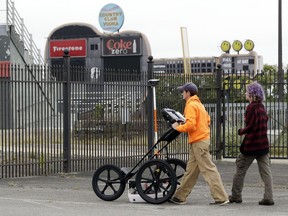 In this Oct. 12, 2017 photo, Greer Stadium, field technicians Chandler Burchfield, left, and Cristina Oliveira use ground penetrating radar in the parking lot of Greer Stadium, a former minor-league baseball park, in Nashville, Tenn. Archaeologists are surveying the stadium for hints of unmarked graves of slaves and free black men who died building Fort Negley next door. Nashville is considering plans to demolish the stadium for housing, entertainment and a park. Historical groups want the land preserved as park space. (AP Photo/Mark Humphrey)