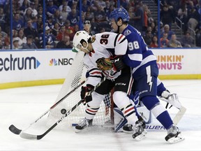 Tampa Bay Lightning defenseman Mikhail Sergachev (98) moves Chicago Blackhawks left wing Ryan Hartman (38) from in front of goalie Andrei Vasilevskiy (88) during the first period of an NHL hockey game Wednesday, Nov. 22, 2017, in Tampa, Fla. (AP Photo/Chris O'Meara)