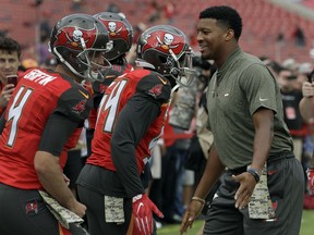 Injured quarterback Jameis Winston, right, shakes hands with the team as they go onto the field before an NFL football game against the New York Jets Sunday, Nov. 12, 2017, in Tampa, Fla. Winston reinjured his shoulder during last week's game in New Orleans. (AP Photo/Chris O'Meara)