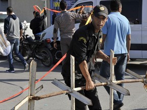 A Tunisian police officer secures the area after a suspected Islamic extremist stabbed two police officers near the Parliament headquarters in Tuni,s Wednesday, Nov.1, 2017. The Tunisian Interior Ministry said in a statement that the attacker was known to authorities for radicalism and that he attacked the officers Wednesday in the name of jihad. (AP Photo/Hassene Dridi)