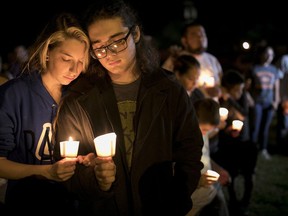 Bailey LeJeaune, 17, and David Betancourt, 18, hold candles during a vigil in Sutherland Springs for the victims of a deadly shooting at the First Baptist Church in Sutherland Springs, Texas, Sunday, Nov. 5, 2017. A man opened fire inside of the church in the small South Texas community on Sunday, killing more than 20 people. (Jay Janner/Austin American-Statesman via AP)
