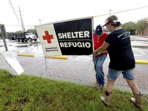 FILE - In this Aug. 25, 2017, file photo, volunteers set up signage outside the Civic Center, where the Red Cross has set up a shelter for those who evacuated their homes due to storm damage in Beaumont, Texas. Texas Gov. Greg Abbott said Wednesday, Nov. 1, 2017 he raised concerns with the American Red Cross following Hurricane Harvey that donated money wasn't getting to people who need it. (Kim Brent/The Beaumont Enterprise via AP, File)