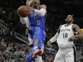 Oklahoma City Thunder guard Russell Westbrook (0) drives to the basket past San Antonio Spurs defenders Danny Green and LaMarcus Aldridge (12) during the first half of an NBA basketball game, Friday, Nov. 17, 2017, in San Antonio. (AP Photo/Eric Gay)