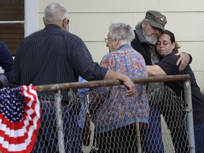 Veteran and Sutherland Springs First Baptist Church member Ted Montgomery, second from right, gets a hug from a friend following a Veterans Day event, Saturday, Nov. 11, 2017, in Sutherland Springs, Texas. A man opened fire inside the church in the small South Texas community on Sunday, killing more than two dozen people. (AP Photo/Eric Gay)