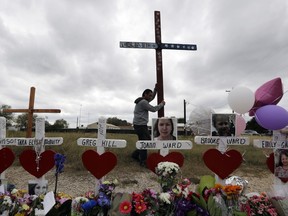 Miguel Zamora stands a cross for the victims of the Sutherland Springs First Baptist Church shooting at a makeshift memorial, Saturday, Nov. 11, 2017, in Sutherland Springs, Texas. A man opened fire inside the church in the small South Texas community on Sunday, killing more than two dozen. Zamora carried the cross for three days to reach the site. (AP Photo/Eric Gay)