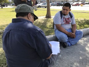In this Oct. 5, 2017 photo, Guillermo Miranda Vazquez, right, speaks to Francisco Pacheco, left, an organizer surveying day laborers about their work conditions in Houston. Vazquez starts his day in a parking lot near the Home Depot where he easily finds work alongside other day laborers who are cleaning up Houston after Hurricane Harvey. (AP Photo/Nomaan Merchant)