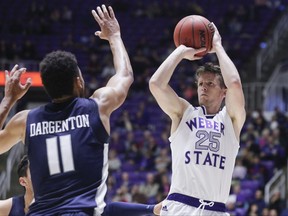 Weber State's Dusty Baker (25) shoots a 3-pointer while being guarded by Utah State's Alex Dargenton (11) during the first half of an NCAA college basketball game Friday, Nov. 10, 2017, in Ogden, Utah. (Matt Herp/Standard-Examiner via AP)