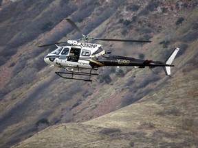 Law enforcement officials in a in a helicopter comb the hills near the mouth of Red Butte Canyon in Salt Lake City on Tuesday, Oct. 31, 2017,  in search of the gunman responsible for the shooting a University of Utah student during a fatal carjacking attempt near the University of Utah late Monday.  (Ravell Call/The Deseret News via AP)