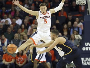 Virginia guard Kyle Guy (5) uses his foot to block a pass by UNC-Greensboro guard Demetrius Troy (11) during an NCAA college basketball game in Charlottesville, Va. (Andrew Shurtleff /The Daily Progress via AP)