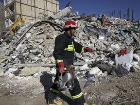 A rescue worker walks past the rubble of a collapsed building at an earthquake site in Sarpol-e-Zahab in western Iran, Tuesday, Nov. 14, 2017. Rescuers are digging through the debris of buildings fallen by Sunday's earthquake in the border region of Iran and Iraq. (AP Photo/Vahid Salemi)