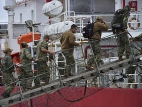 US sailors embark on the Sophie Siem ship in Comodoro Rivadavia port, Argentina, on Sunday, Nov. 26, 2017. The ship carries the US Navy pressurized rescue module that will be used in the search of the missing Argentine submarine ARA San Juan. (AP Photo/Maxi Jonas)
