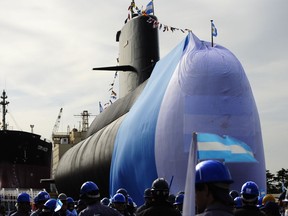 In this Sept. 27, 2011 photo, workers stand around the ARA San Juan submarine during a ceremony celebrating the first stage of major repairs at the Argentine Industrial Naval Complex (CINAR) in Buenos Aires. President Mauricio Macri said on Friday, Nov. 24, 2017 the international search for the submarine carrying 44 crew members that has been lost in the South Atlantic since Nov. 15 will continue and that the sub's disappearance will be investigated. (AP Photo/Mario Defina)