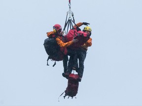 Search and rescue members on a long line steady Annette Poitras while being lowered to the ground by a helicopter after rescuing her from Eagle Mountain in Coquitlam, B.C., on Wednesday November 22, 2017. A Vancouver-area woman missing since Monday has been found alive after she disappeared while out walking three dogs. THE CANADIAN PRESS/Darryl Dyck