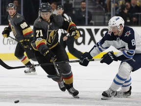William Karlsson, left, of the Vegas Golden Knights, fights off the checking of Winnipeg Jets' Jacob Trouba during NHL action Friday night in Las Vegas. Karlsson had a pair of goals to lead the Golden Knights to a 5-2 victory.