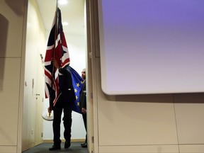 Members of protocol walk out from backstage as they prepare to put up the British and EU flags prior to a media conference of European Union chief Brexit negotiator Michel Barnier and British Secretary of State for Exiting the European Union David Davis at EU headquarters in Brussels on Friday, Nov. 10, 2017. The EU and Britain conducted a sixth round of Brexit negotiations on Friday. (AP Photo/Virginia Mayo)