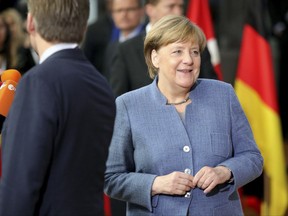 German Chancellor Angela Merkel, right, speaks with journalists as she arrives for an Eastern Partnership Summit in Brussels, Friday, Nov. 24, 2017. European Union leaders meet with their counterparts from Armenia, Azerbaijan, Belarus, Georgia, Moldova and Ukraine for a summit in Brussels on Friday November 24. British Prime Minister Theresa May is also due to hold separate talks with her EU partners. (AP Photo/Olivier Matthys)