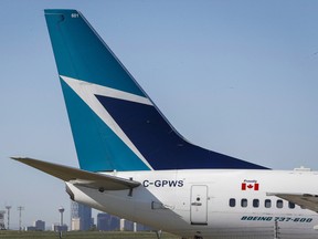 The tail of a WestJet plane is shown by the Calgary skyline on May 3, 2016.