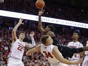 Xavier's Naji Marshall, fouls Wisconsin's Brad Davison (34) during the first half of an NCAA college basketball game Thursday, Nov. 16, 2017, in Madison, Wis. At left is Wisconsin's Ethan Happ (22) and at right is Aleem Ford. (AP Photo/Andy Manis)
