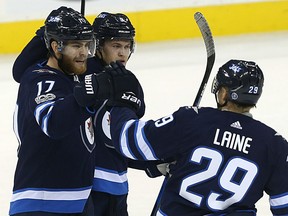 Jets forwards Patrik Laine and Andrew Copp, centre, congratulate Adam Lowry on his goal against the Arizona Coyotes in Winnipeg on Tuesday night.