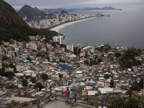 In this Oct. 29, 2017 photo published Monday, Nov. 13, men overlook the city from the Vidigal slum, in Rio de Janeiro, Brazil. Opening the hillside favelas to tourists seemed like a winning idea: they get breathtaking views, the slum residents could cash in, and foreign visitors would see another part of the city, but soaring violence has rekindled a concern about safety. (AP Photo/Renata Brito)