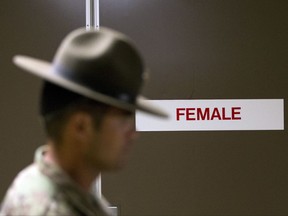 In this Oct. 4, 2017, photo, a U.S. Army drill instructor walks past a barracks for female recruits at Ft. Benning, Ga. The Army's introduction of women into the infantry has moved steadily but cautiously this year. As home to the previously all-male infantry and armor schools, Fort Benning had to make a number of adjustments, including female dorm rooms, security cameras, monitoring stations. (AP Photo/John Bazemore)