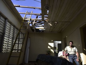 In this Nov. 15, 2017 photo, Edgardo de León sits in his living room with a hole in the ceiling caused by the whip of hurricane Maria, in Cataño, Puerto Rico.   A newly created Florida company with an unproven record won more than $30 million in contracts from the Federal Emergency Management Agency to provide emergency tarps and plastic sheeting for repairs to hurricane victims in Puerto Rico. Bronze Star LLC never delivered those urgently needed supplies, which even months later remain in demand on the island.  (AP Photo/Carlos Giusti)