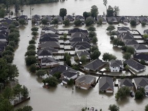 FILE - In this Tuesday, Aug. 29, 2017, file photo, homes are surrounded by floodwaters from Tropical Storm Harvey in Spring, Texas. The House has passed legislation that will increase flood insurance premiums for many property owners to help firm up a program under stress from ever-more frequent and powerful storms. (AP Photo/David J. Phillip, File)