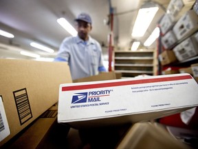 FILE - In this Thursday, Feb. 7, 2013, file photo, packages wait to be sorted in a Post Office as U.S. Postal Service letter carrier Michael McDonald, gathers mail to load into his truck before making his delivery run, in Atlanta. As consumers demand ever-quicker and convenient package delivery, the U.S. Postal Service wants to boost its business this holiday season by offering what few e-commerce retailers can provide: cheap next-day service with packages delivered Sundays to your home. (AP Photo/David Goldman, File)