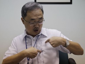 State Prosecutor Senior Assistant Peter Ong points to his chest to show where bullets hit the Italian Catholic missionary Rev. Fausto Tentorio during an interview at the Department of Justice in Manila, Philippines, Friday, Nov. 10, 2017. Ong said the Philippine government militiamen gunned down Tentorio in a 2011 attack, which state prosecutors say may have been carried out with the knowledge of two army commanders in the country's south. (AP Photo/Aaron Favila)