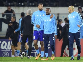 Marseille's Patrice Evra, center right, is led away by his teammate Rolando after a scuffle with Marseille supporters who trespassed into the field before the Europa League group I soccer match between Vitoria SC and Olympique de Marseille at the D. Afonso Henriques stadium in Guimaraes, Portugal, Thursday, Nov. 2, 2017. Evra was shown a red card before the start of the match for his involvement in the incident. (AP Photo/Luis Vieira)