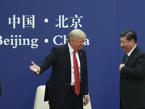 U.S. President Donald Trump, left, shows the way to Chinese President Xi Jinping on stage during a business event at the Great Hall of the People in Beijing, Thursday, Nov. 9, 2017. Trump is on a five-country trip through Asia traveling to Japan, South Korea, China, Vietnam and the Philippines. (AP Photo/Andy Wong)