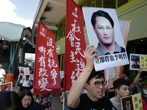 FILE - In this Sept. 11, 2017, file photo, a protester raises a picture of Taiwanese activist Lee Ming-che during a demonstration outside the Chinese liaison office in Hong Kong. A Chinese court on Tuesday, Nov. 28, 2017, has sentenced to five years in prison the Taiwanese activist who conducted online lectures on Taiwan's democratization and managed a fund for families of political prisoners in China. (AP Photo/Vincent Yu, File)