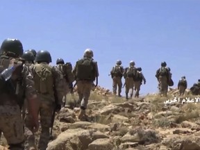 FILE - This file frame grab from video released on Saturday, July 22, 2017 and provided by the government-controlled Syrian Central Military Media, shows Hezbollah fighters advancing up a hill during clashes with al-Qaida-linked militants in an area on the Lebanon-Syria border. Syria's long-running civil war may be winding down, but even if the conflict ends, Syria is a changed country with a dizzying array of local militias and thousands of foreign troops, some of whom may never leave. (Syrian Central Military Media, via AP, File)